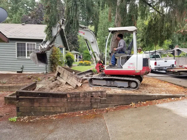 Excavator removing an old timber retaining wall