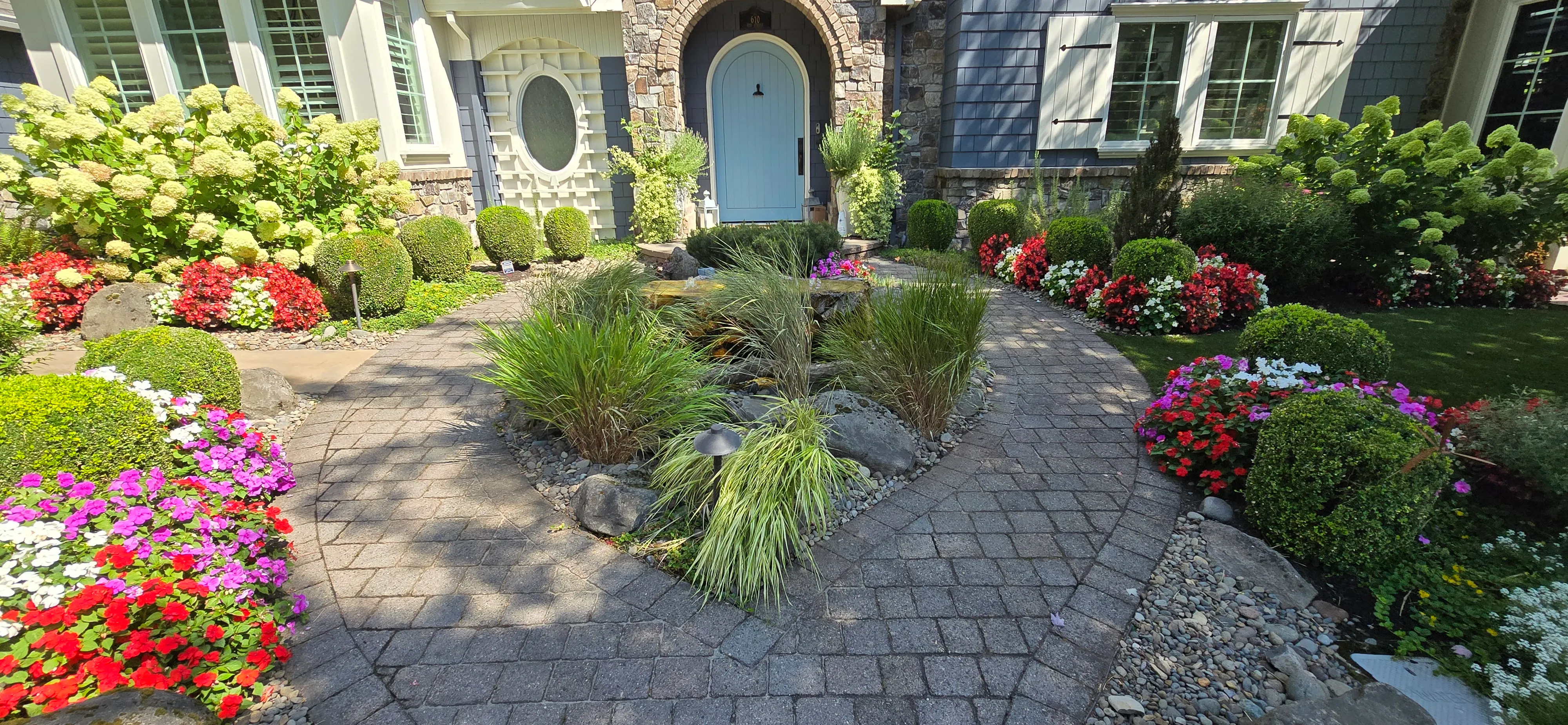 The same entry walk in summer with a basalt bubbler in the island and borders full of color