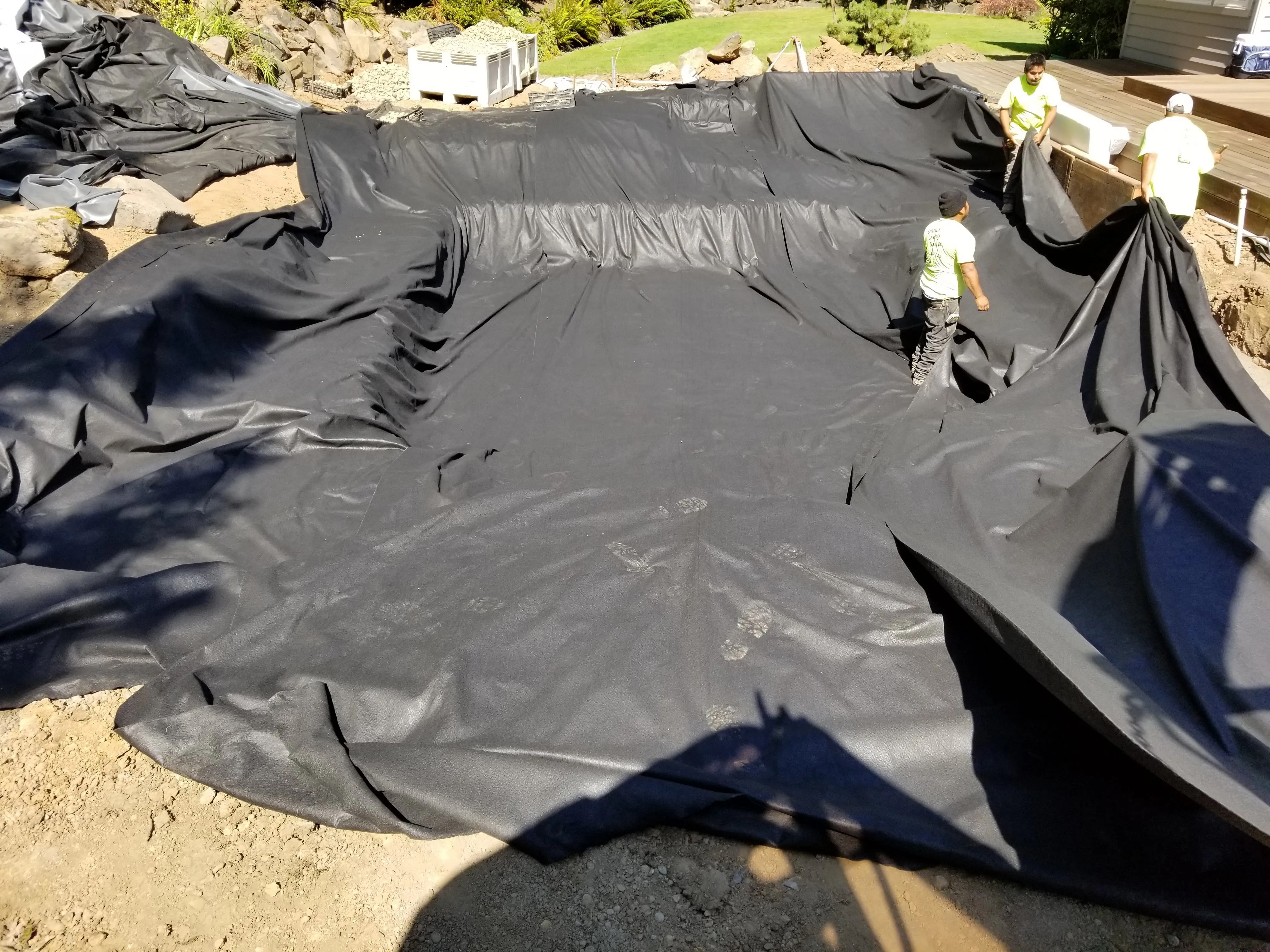 Underlayment and liner spread across the excavated pond basin