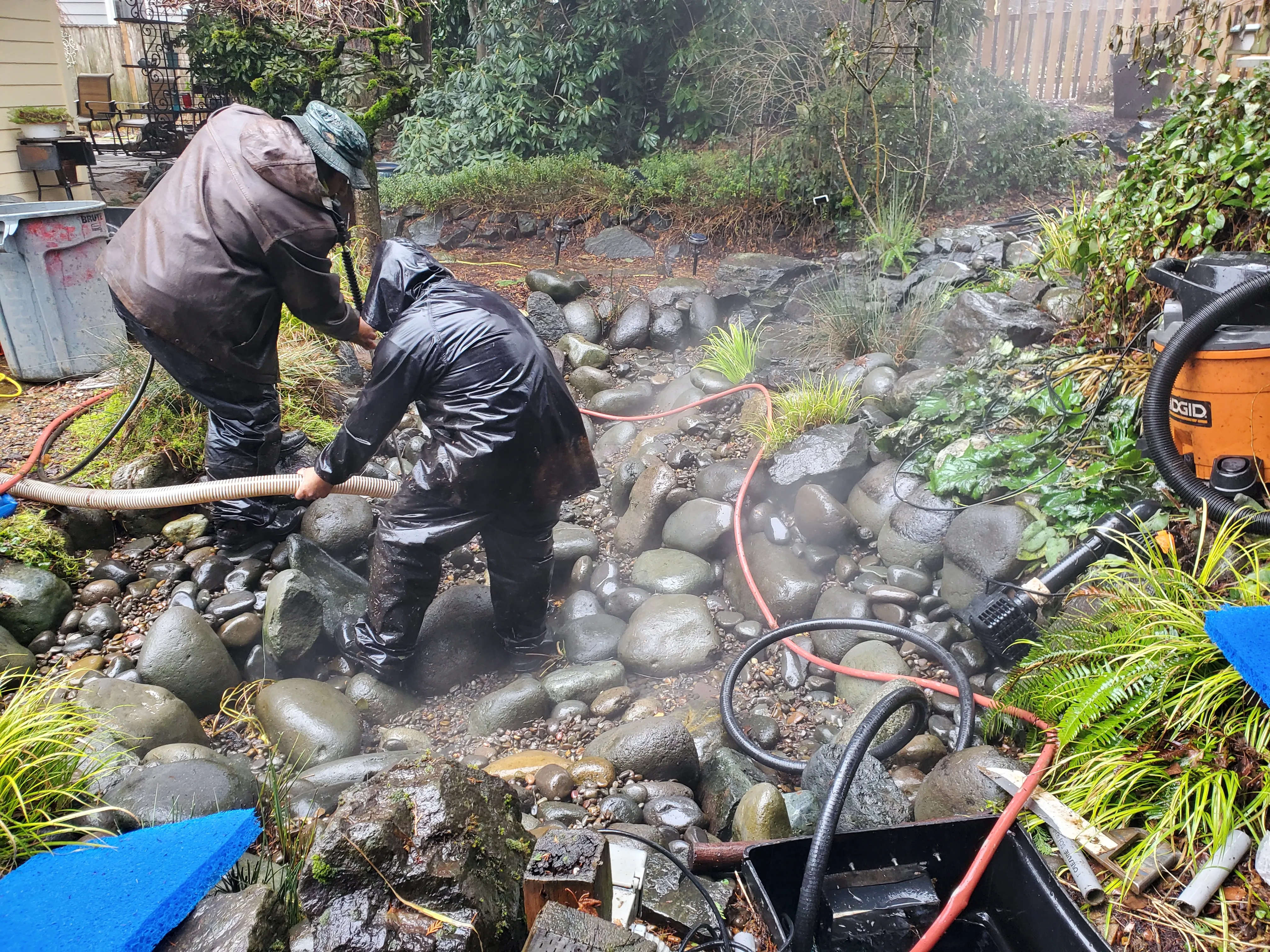 Earthworks crew vacuuming out a stream bed during a pond cleanout