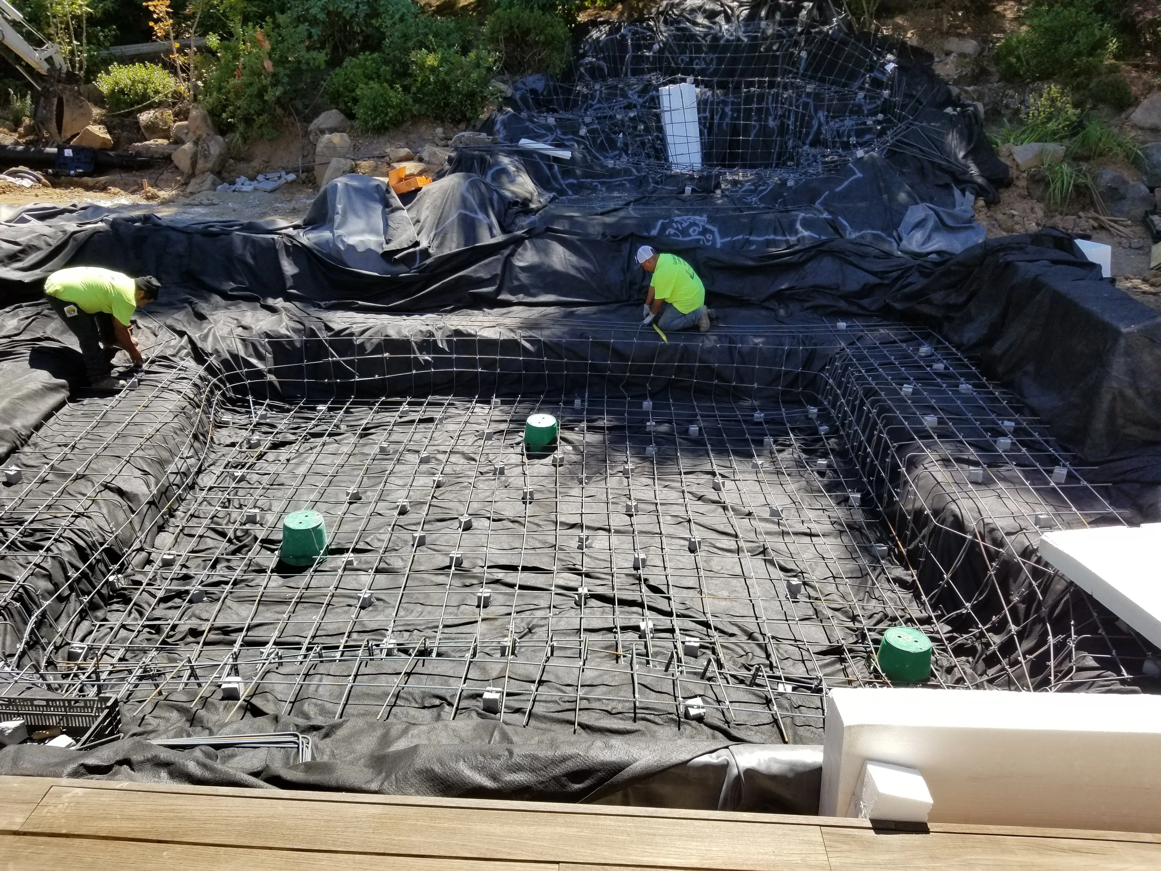 Crew tying a full steel grid over the lined pond basin before the shell went in