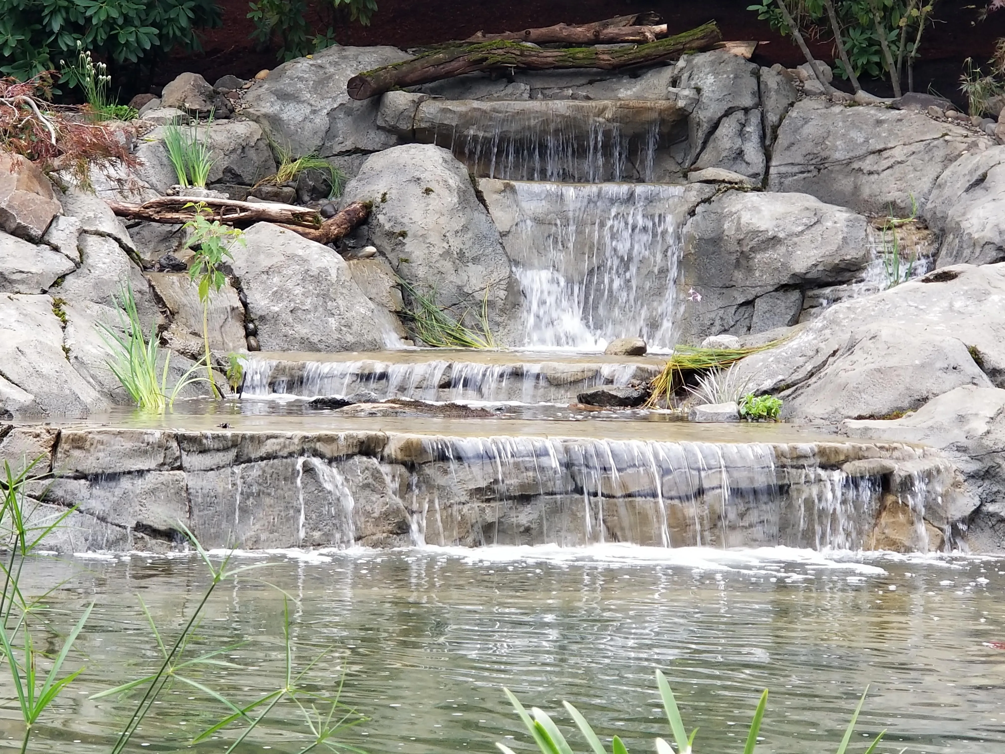 Twin stacked-stone waterfalls pouring into the new pond