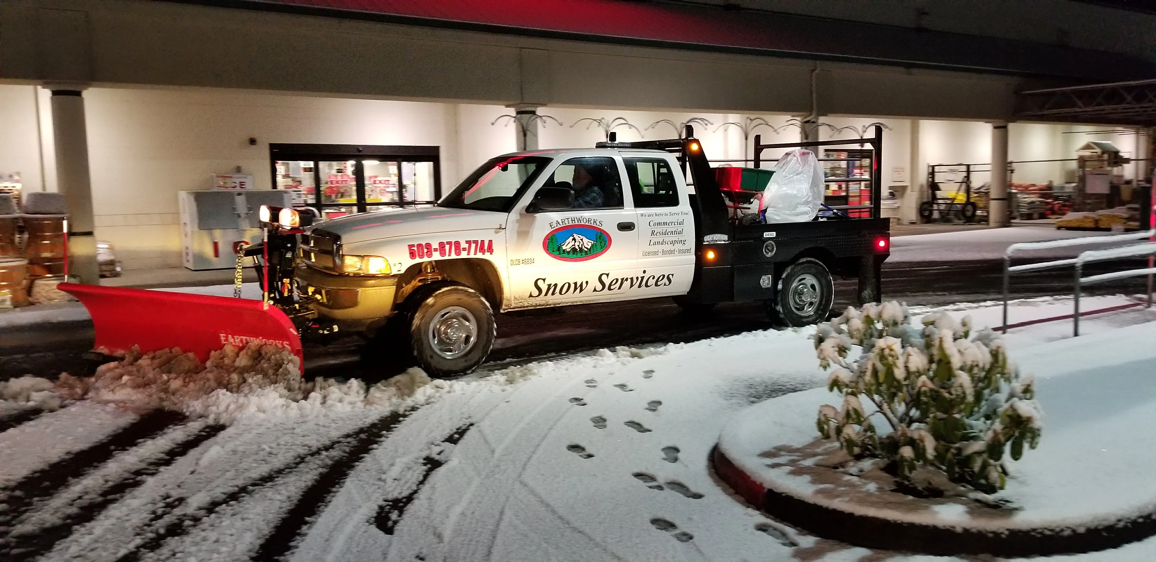 Earthworks snow plow truck clearing a commercial parking lot overnight