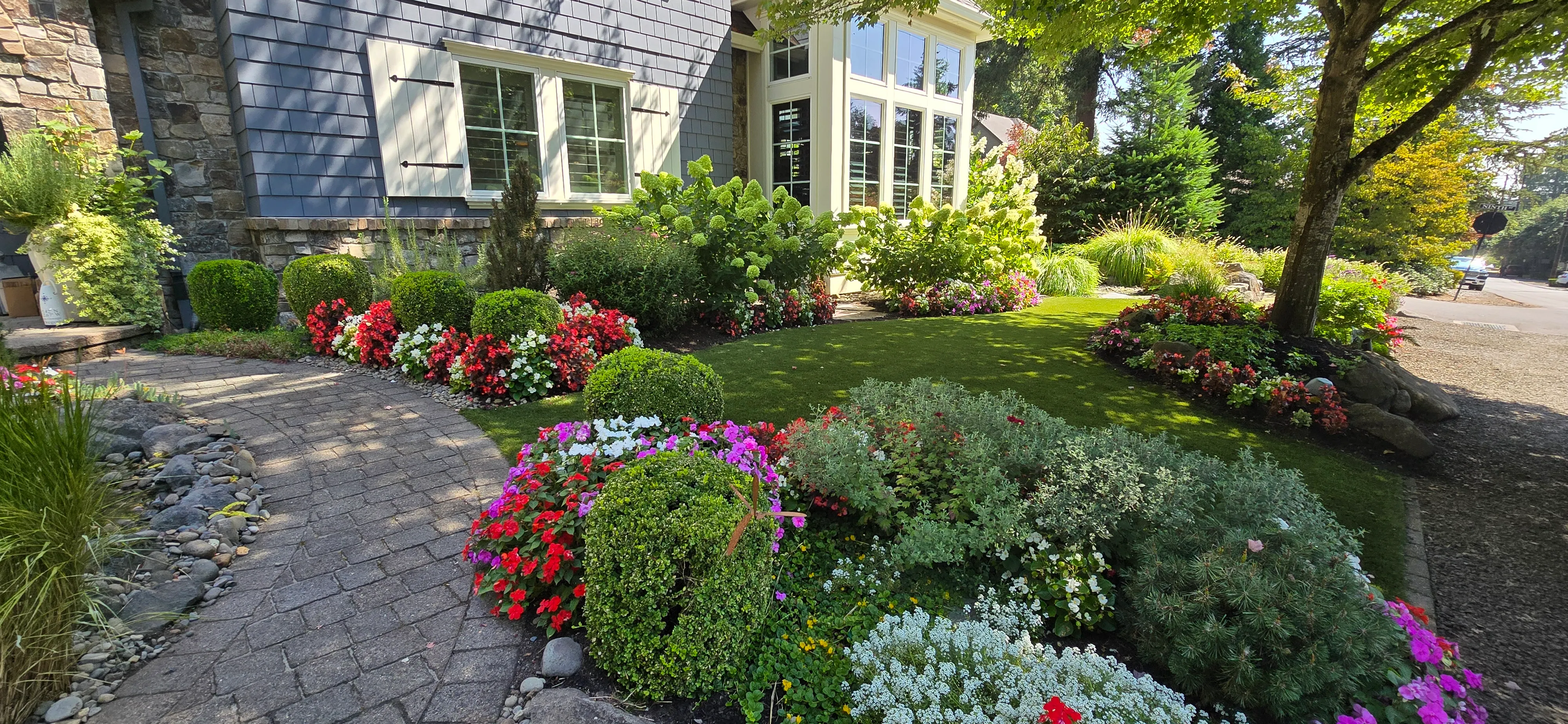 Artificial turf lawn holding uniform green behind beds full of color spots