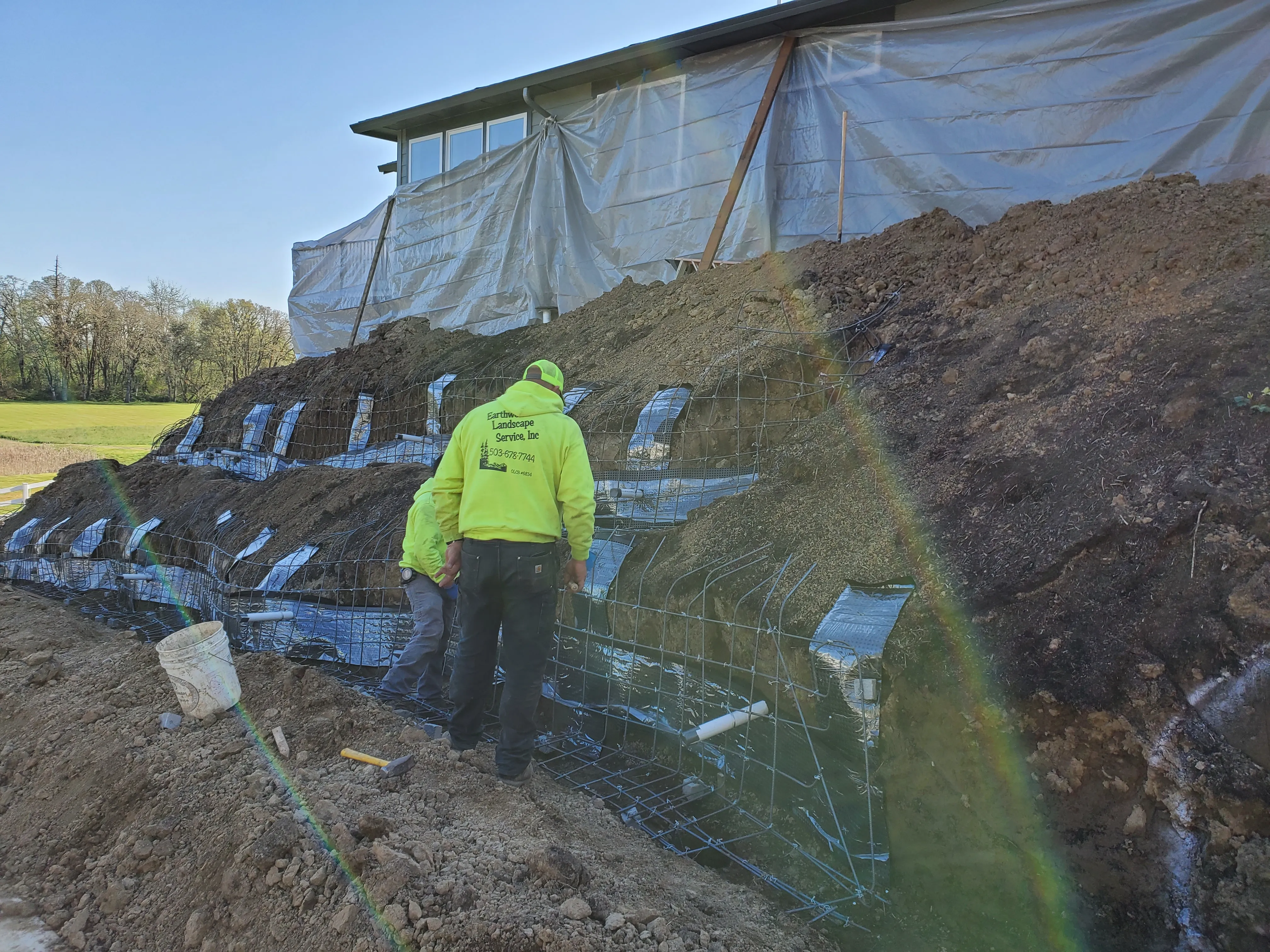 Earthworks crew member at the foil-wrapped wall forms set into the excavated slope