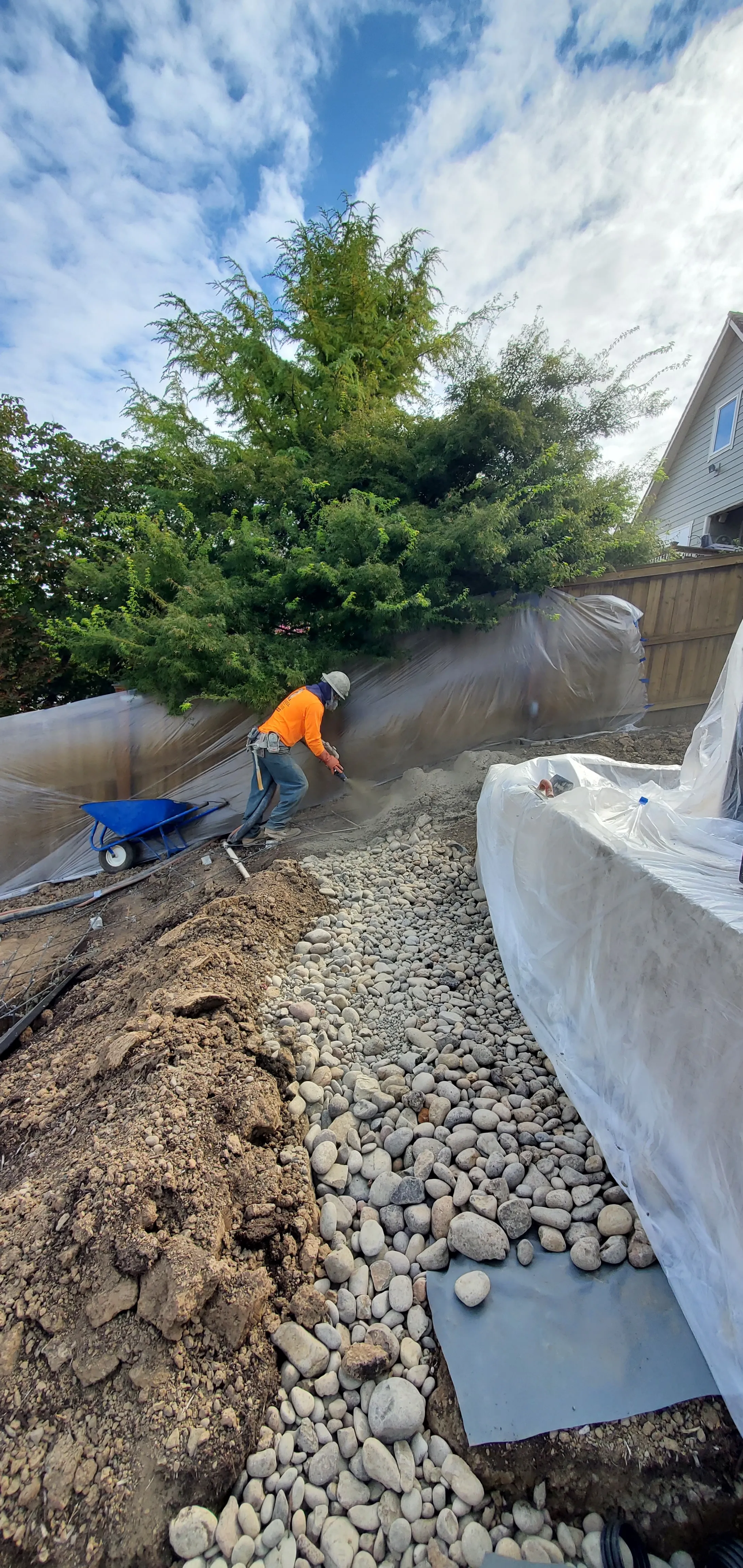 Earthworks carver shaping the wet concrete wall face into boulder texture by hand