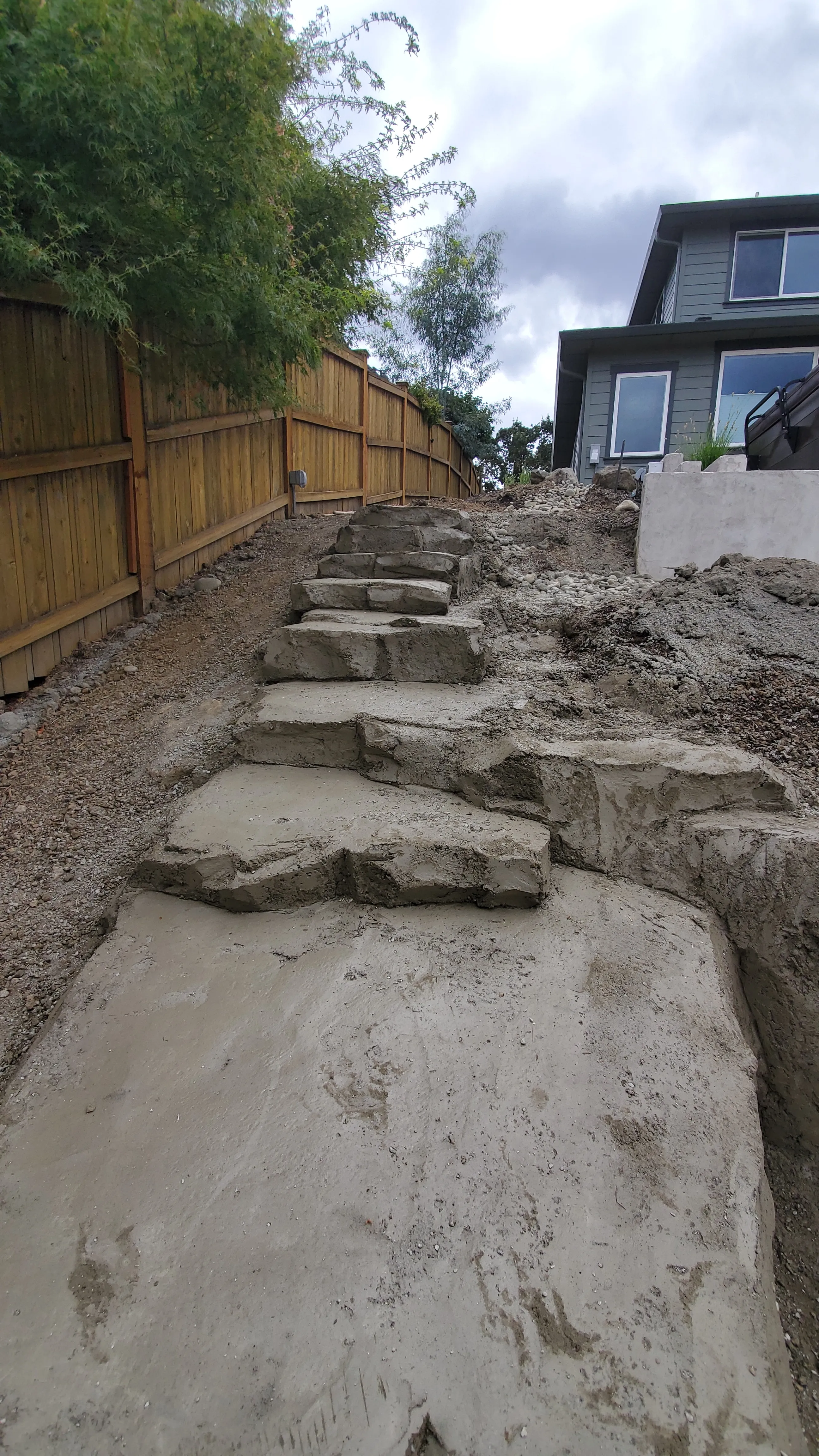 Carved concrete steps climbing the open slope mid-build, edges still rough