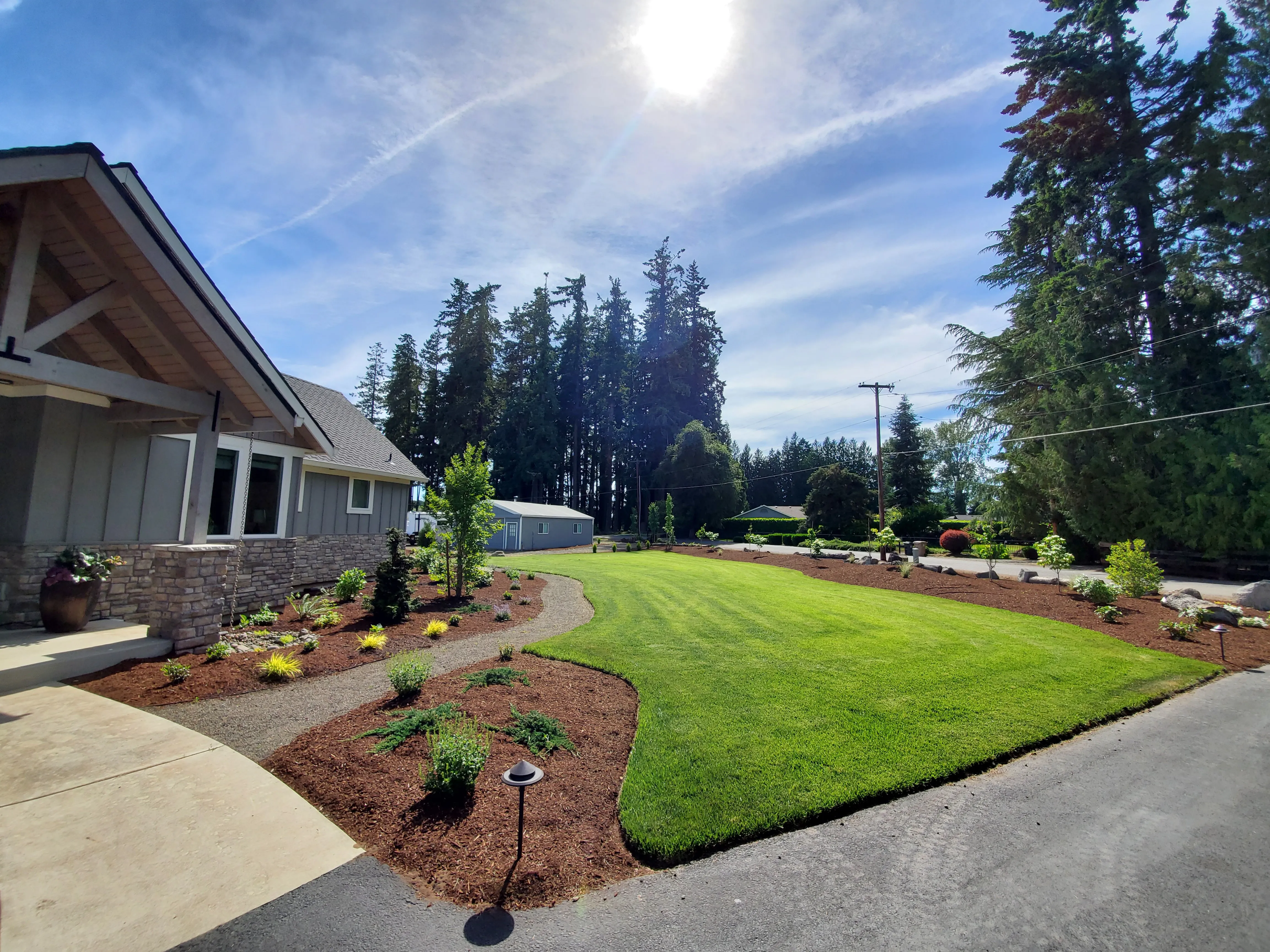 New craftsman front yard in Aurora with fresh sod, curved gravel path, and young planting beds