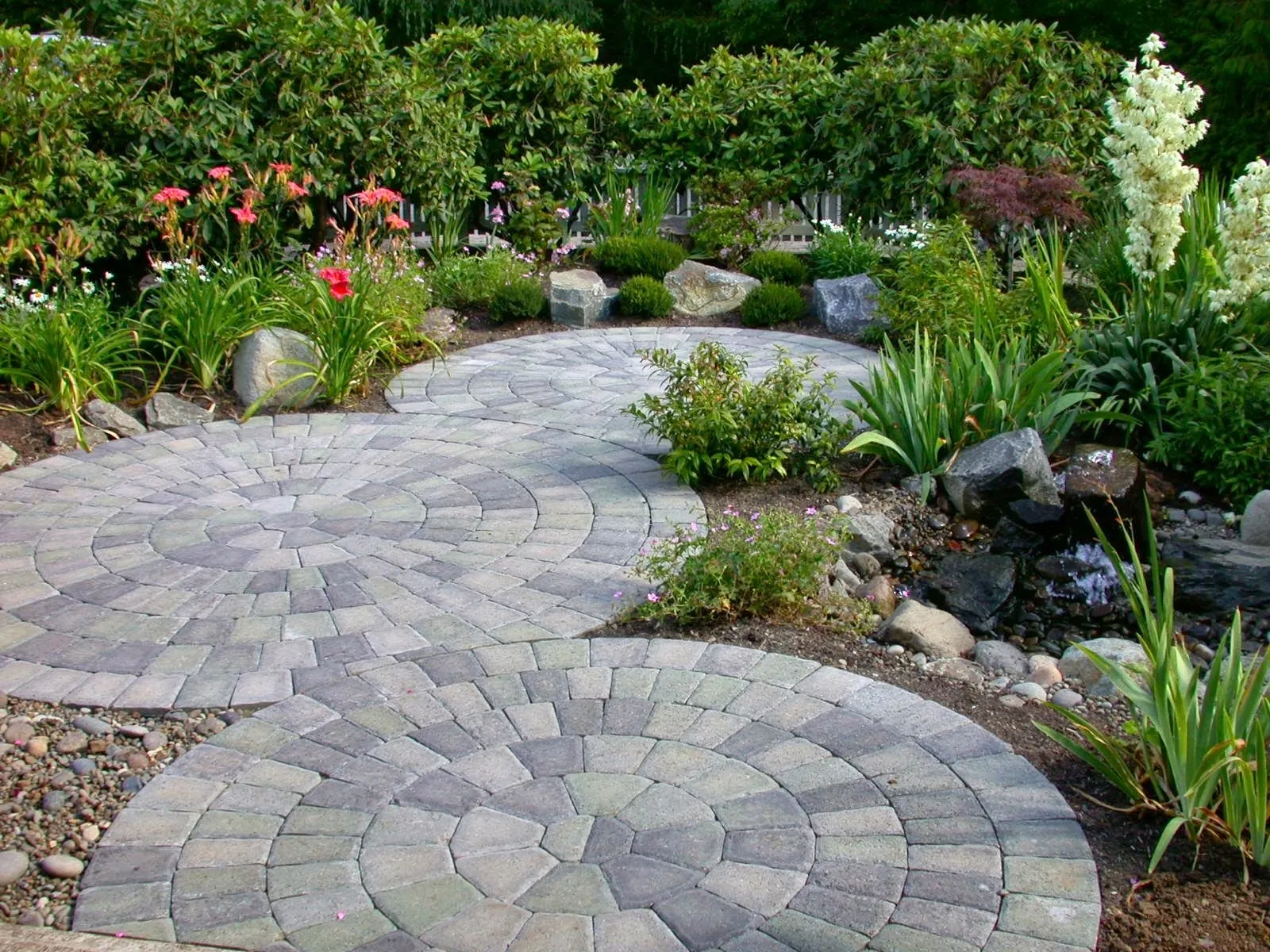 Linked circle-pattern paver path through a planted garden with a small stream in Oregon City