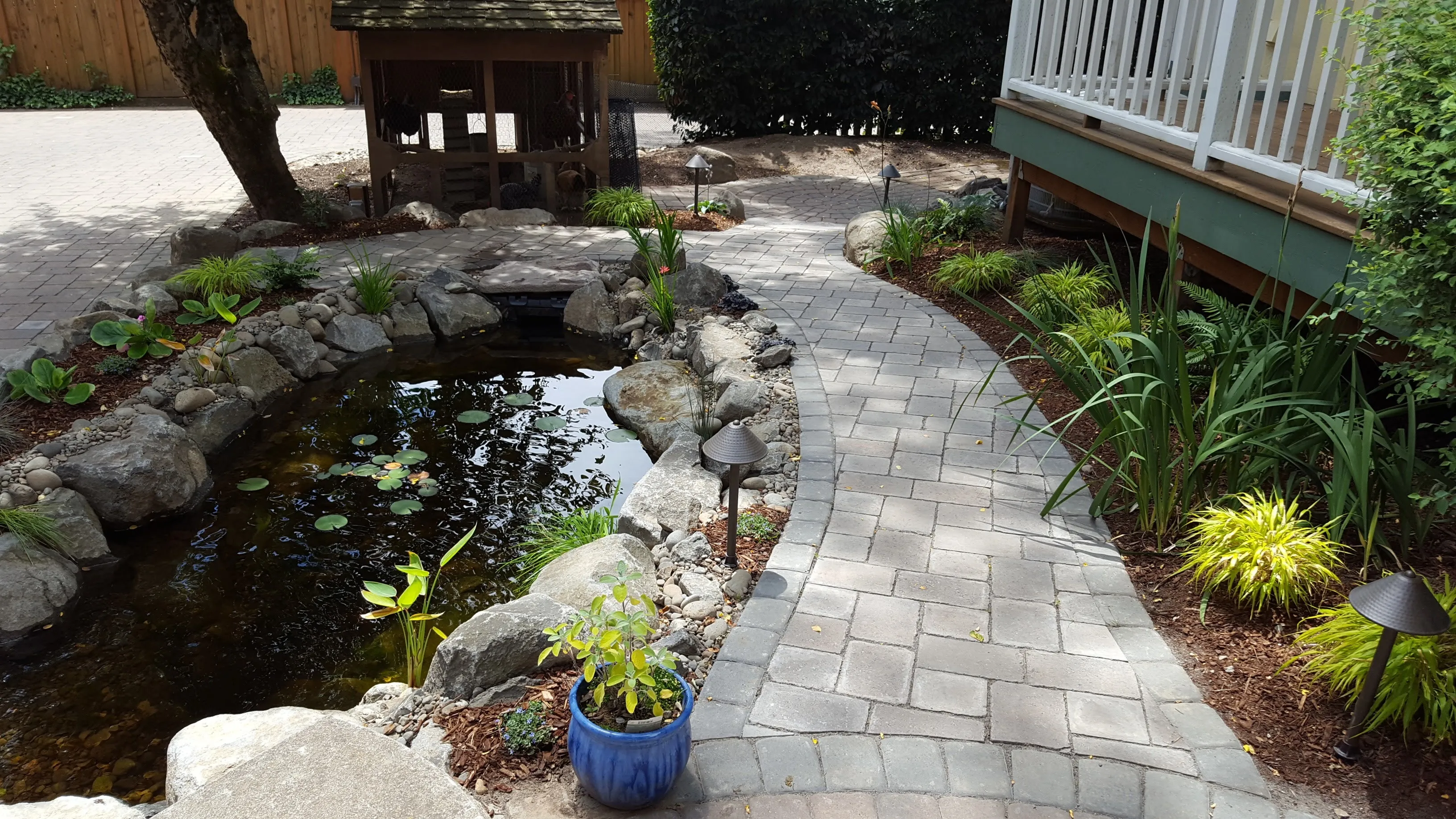 Paver garden path tracing a pond edge with a stone lantern